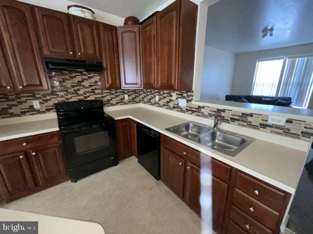 kitchen featuring range hood, black appliances, decorative backsplash, and sink