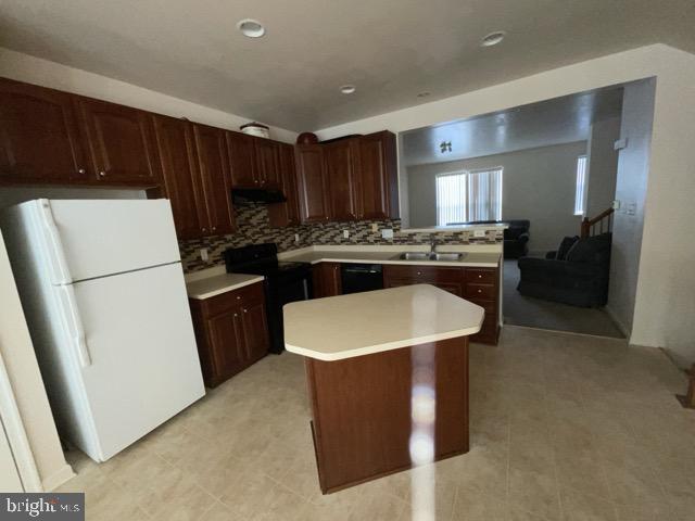 kitchen featuring black appliances, a kitchen island, tasteful backsplash, and sink