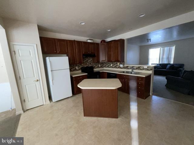 kitchen featuring black range, a kitchen island, white fridge, tasteful backsplash, and sink