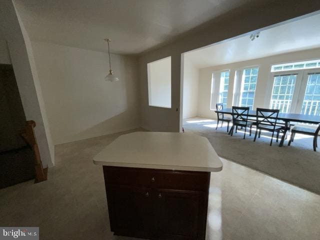 kitchen with light carpet, pendant lighting, and a kitchen island