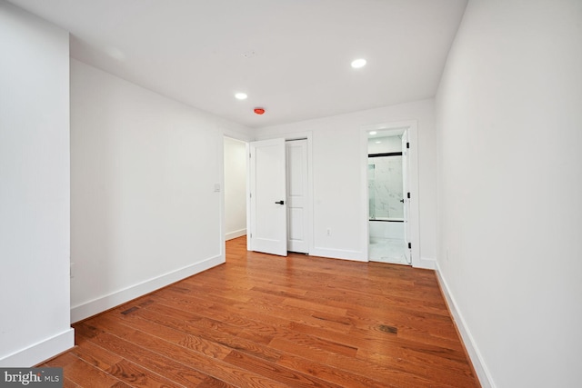 unfurnished bedroom featuring connected bathroom and wood-type flooring