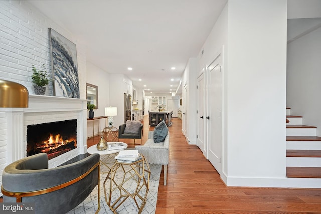 living room featuring light hardwood / wood-style flooring and a brick fireplace