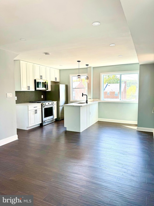 kitchen featuring white cabinets, stainless steel appliances, dark hardwood / wood-style floors, pendant lighting, and tasteful backsplash