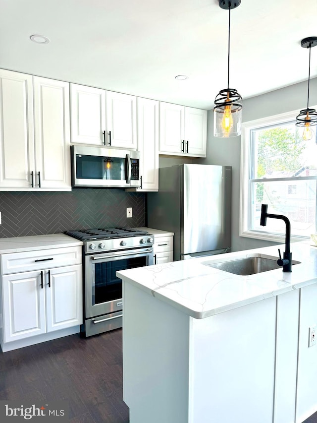 kitchen featuring appliances with stainless steel finishes, hanging light fixtures, decorative backsplash, light stone counters, and white cabinets