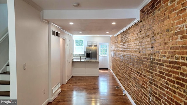 corridor featuring crown molding, brick wall, and dark hardwood / wood-style floors