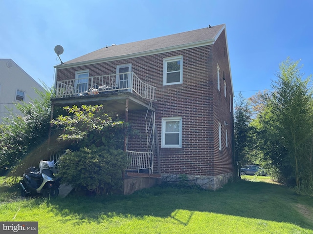 rear view of property featuring a balcony and a yard