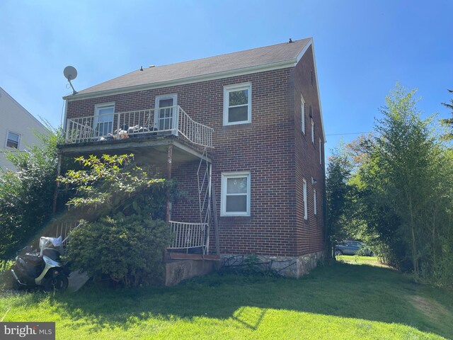 rear view of house with a lawn and a balcony