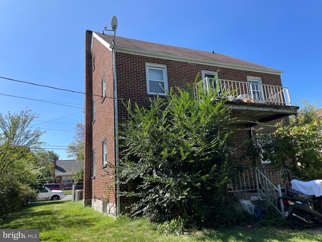 view of home's exterior with a balcony and a lawn