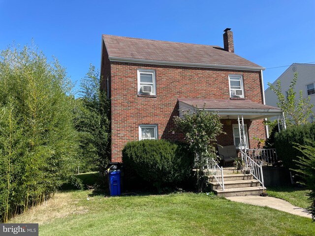 view of front of property featuring a front yard, covered porch, and cooling unit