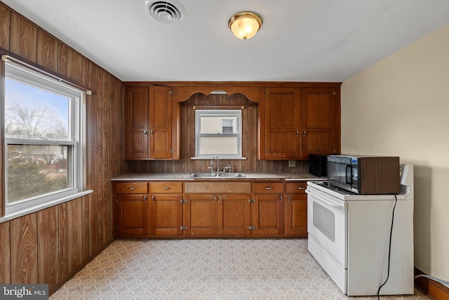 kitchen featuring sink, white electric range, and wooden walls