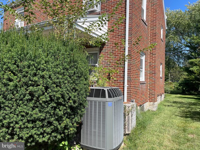 view of side of home with central AC and a yard