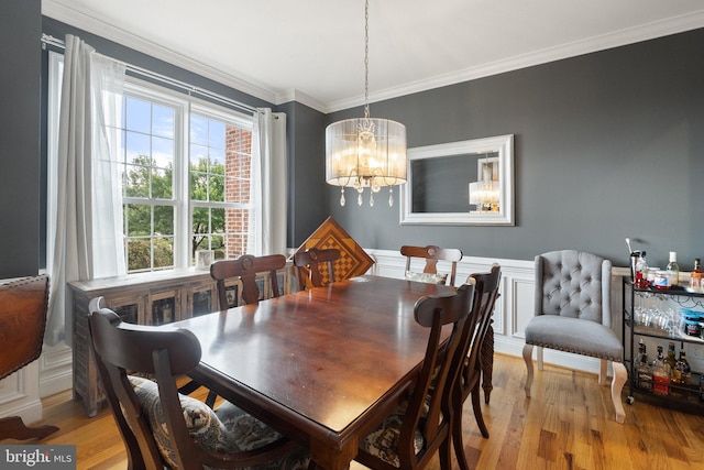 dining room featuring light hardwood / wood-style floors, crown molding, and an inviting chandelier