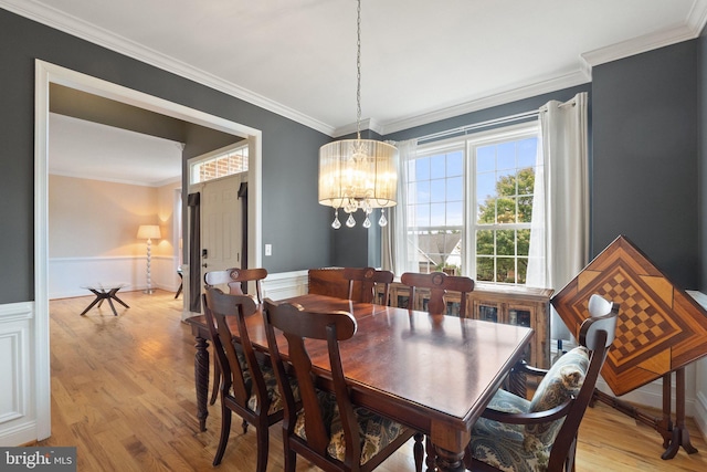 dining area with ornamental molding, a chandelier, and light wood-type flooring