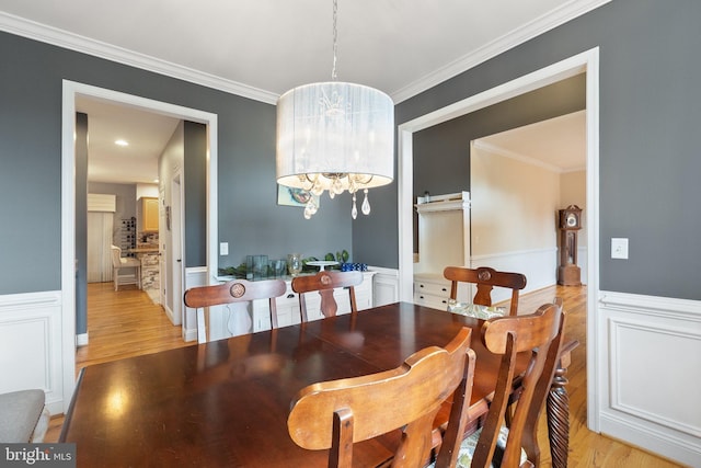 dining room with light hardwood / wood-style flooring, an inviting chandelier, and ornamental molding