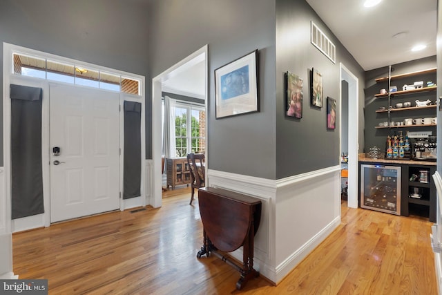 entryway featuring bar, light hardwood / wood-style floors, and wine cooler