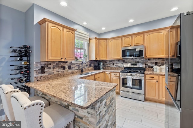 kitchen featuring light stone countertops, sink, light brown cabinets, stainless steel appliances, and kitchen peninsula