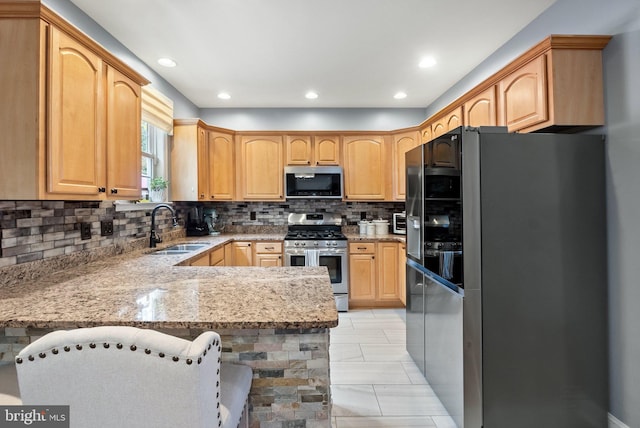 kitchen with sink, decorative backsplash, appliances with stainless steel finishes, light stone counters, and kitchen peninsula