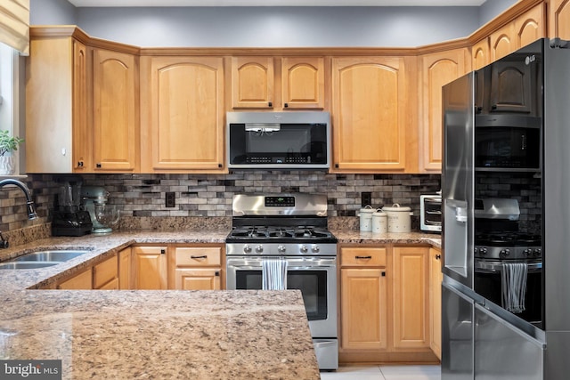 kitchen with appliances with stainless steel finishes, backsplash, light stone counters, and sink