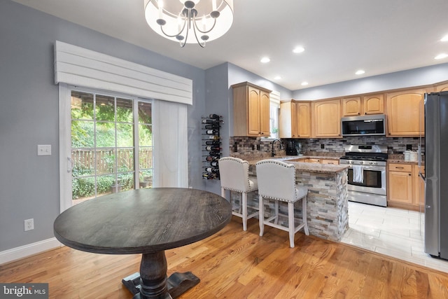 kitchen with a notable chandelier, stone countertops, light wood-type flooring, and appliances with stainless steel finishes