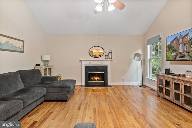 living room featuring ceiling fan, a fireplace, high vaulted ceiling, and light hardwood / wood-style floors