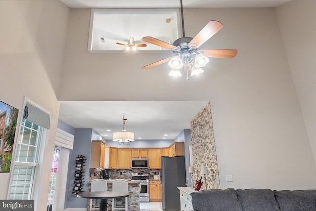 interior space with light brown cabinets, sink, decorative backsplash, ceiling fan, and stainless steel appliances