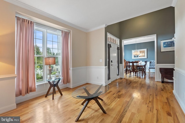 sitting room with hardwood / wood-style flooring, plenty of natural light, crown molding, and a notable chandelier