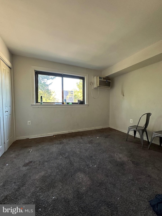 unfurnished bedroom with dark carpet, a closet, and a wall mounted AC