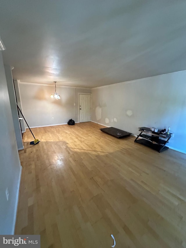 additional living space with light wood-type flooring and a notable chandelier