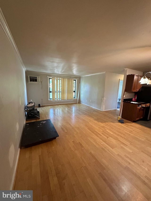 unfurnished living room featuring light hardwood / wood-style floors, crown molding, a chandelier, and a wall mounted air conditioner