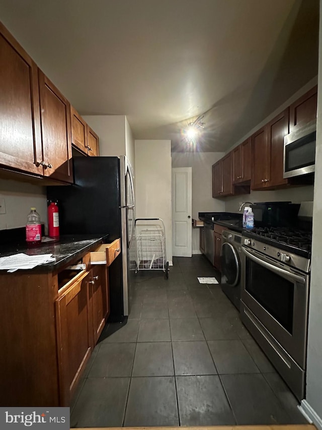 kitchen featuring dark tile patterned flooring, stainless steel appliances, and washer / dryer