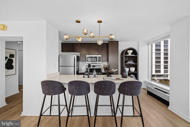 kitchen featuring dark brown cabinetry, sink, appliances with stainless steel finishes, a breakfast bar, and light wood-type flooring