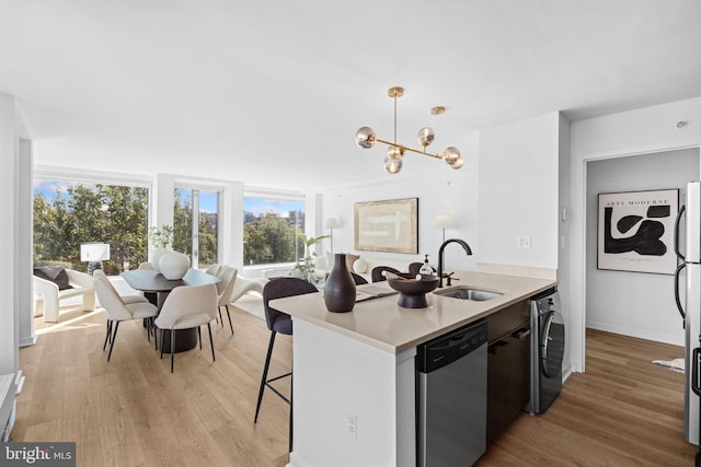 kitchen featuring light wood-type flooring, washer / dryer, appliances with stainless steel finishes, and decorative light fixtures