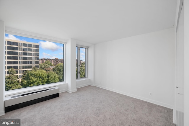 carpeted empty room featuring baseboard heating and a wealth of natural light