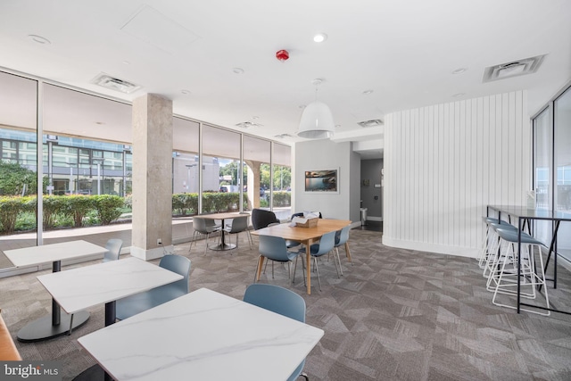 carpeted dining room featuring a wall of windows