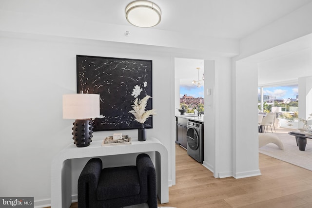 laundry room with an inviting chandelier, light wood-type flooring, washer / dryer, and sink