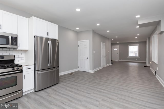 kitchen featuring white cabinets, backsplash, light hardwood / wood-style floors, and appliances with stainless steel finishes