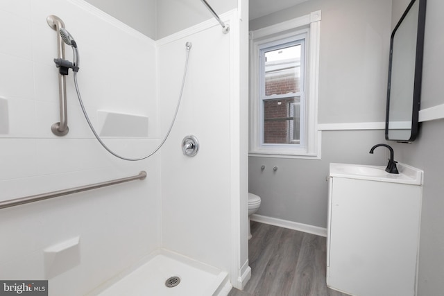 bathroom featuring wood-type flooring, walk in shower, vanity, and toilet