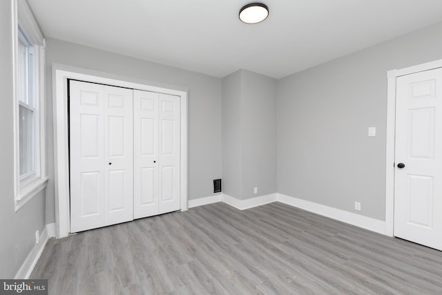 unfurnished bedroom with light wood-type flooring and a closet