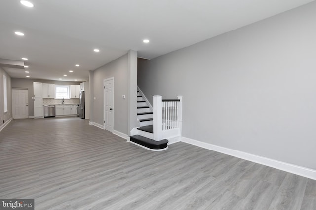 unfurnished living room with light hardwood / wood-style flooring and sink