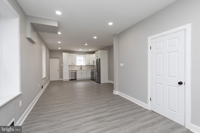 unfurnished living room with light hardwood / wood-style floors and sink