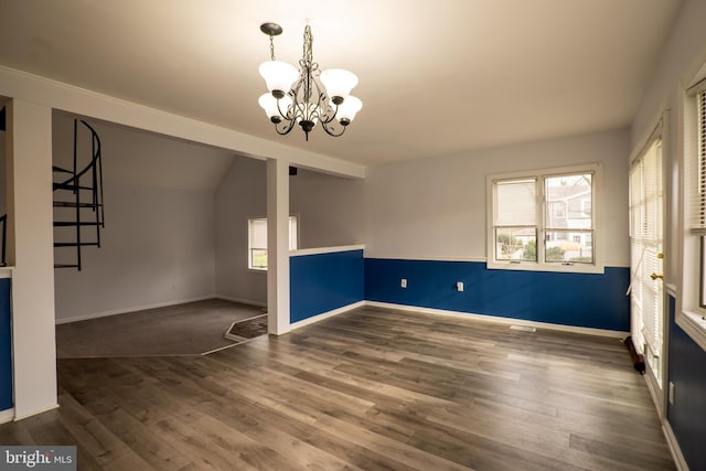 unfurnished room with lofted ceiling, dark hardwood / wood-style floors, and an inviting chandelier