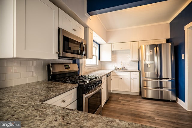 kitchen featuring dark wood-type flooring, appliances with stainless steel finishes, white cabinetry, and dark stone counters