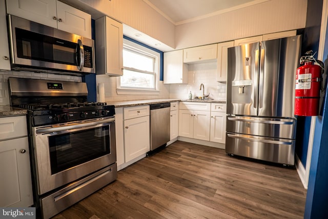 kitchen with light stone counters, stainless steel appliances, white cabinetry, and ornamental molding