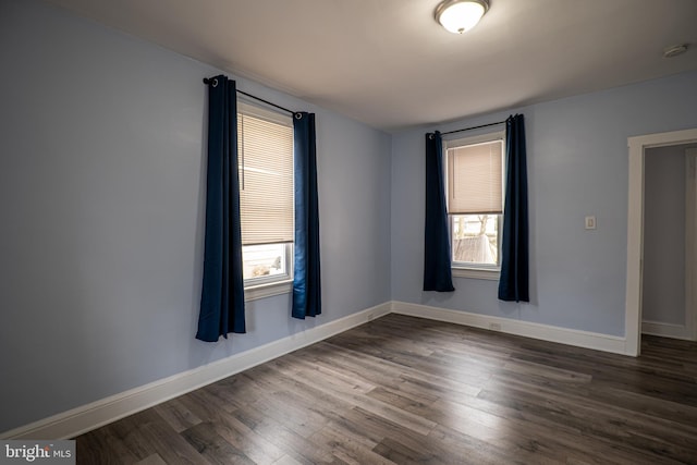 empty room featuring dark wood-type flooring and plenty of natural light