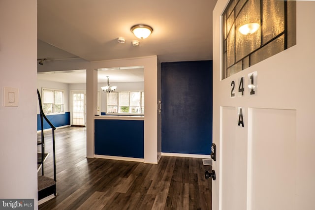 hall featuring dark wood-type flooring and a notable chandelier