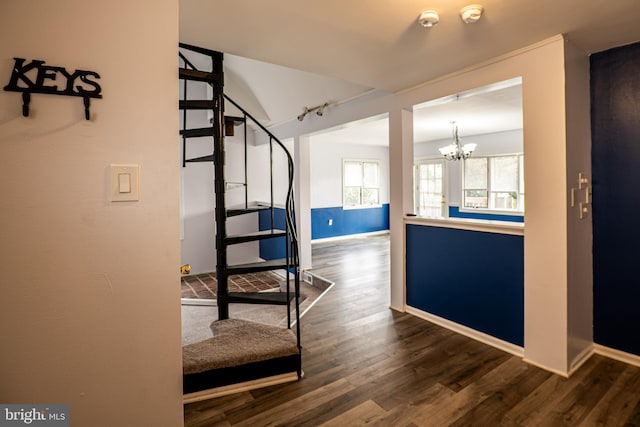 hallway featuring dark wood-type flooring, a chandelier, and track lighting