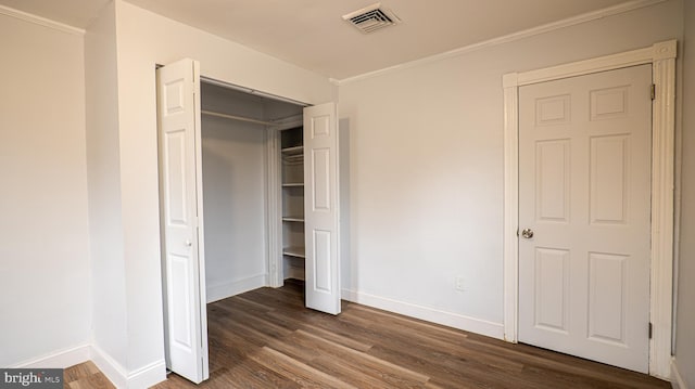 unfurnished bedroom featuring ornamental molding, dark wood-type flooring, and a closet