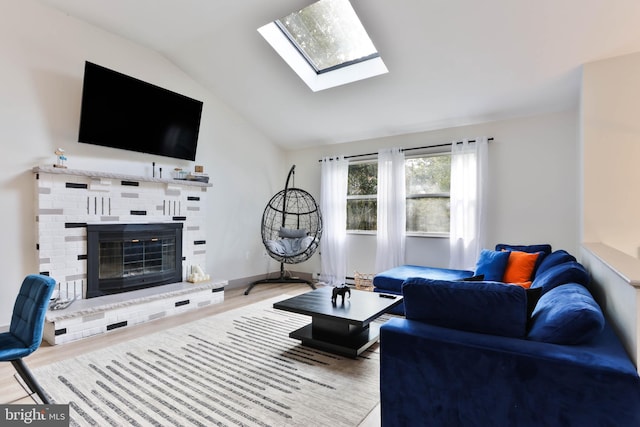 living room featuring wood-type flooring, a fireplace, and vaulted ceiling with skylight