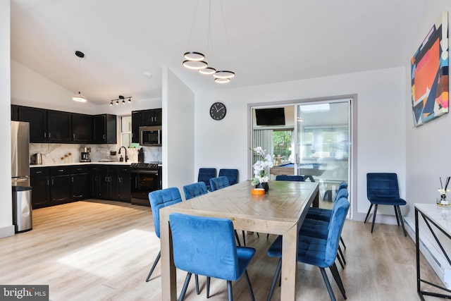 dining space featuring light hardwood / wood-style flooring, lofted ceiling, and sink