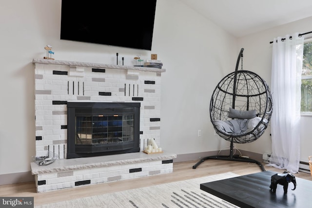 living room featuring a brick fireplace and wood-type flooring